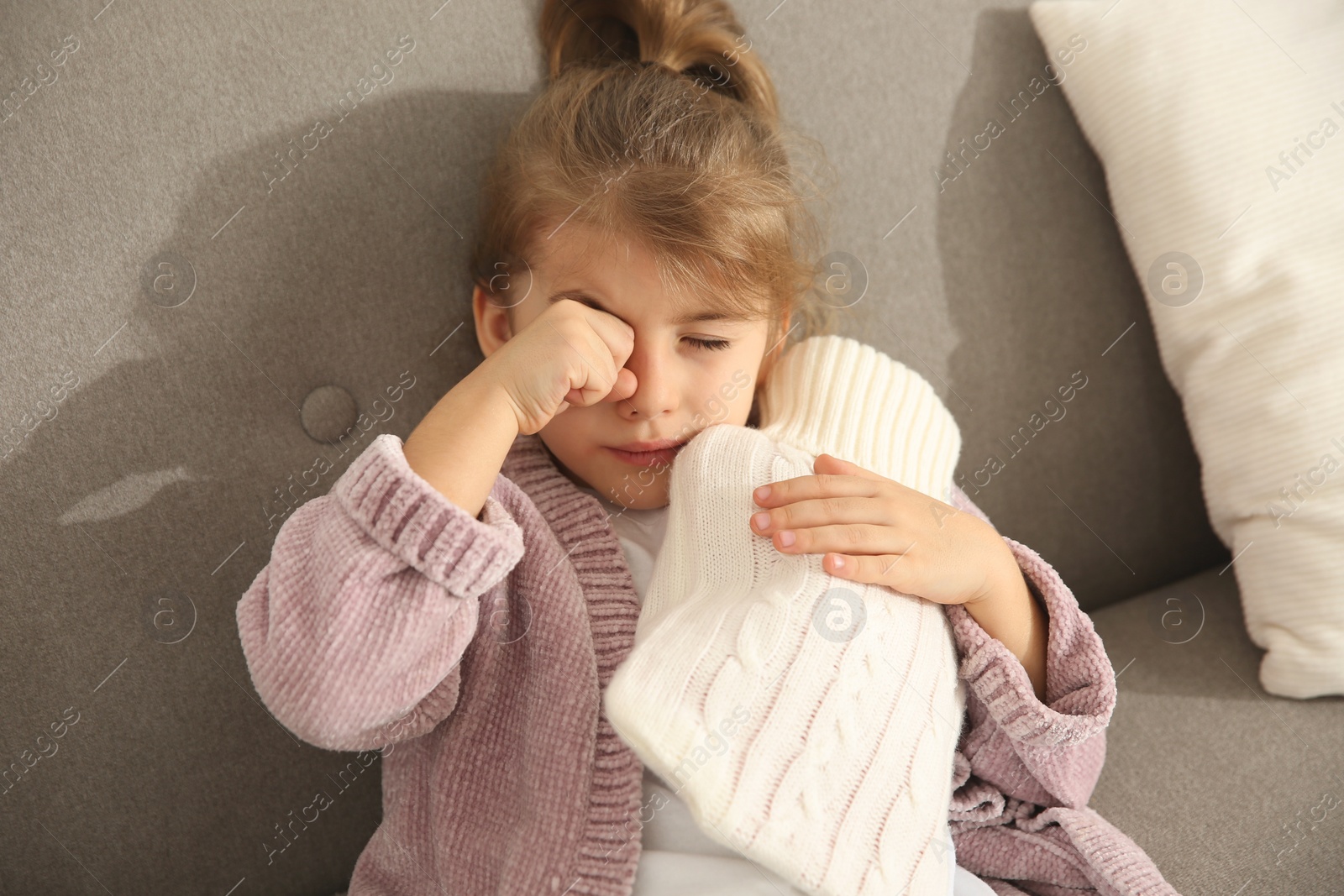 Photo of Ill girl with hot water bottle suffering from cold at home