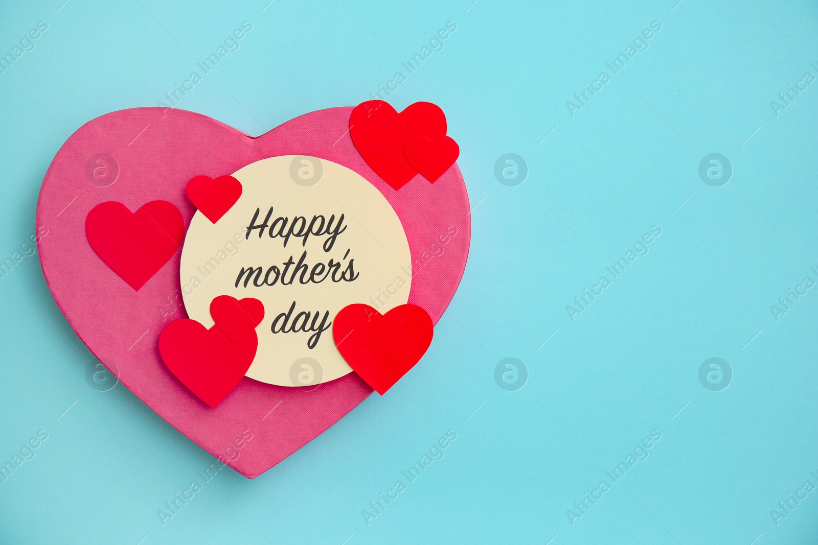 Photo of Surprise for Mother's Day with greeting card and paper hearts on color background