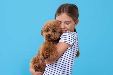 Little child with cute puppy on light blue background. Lovely pet