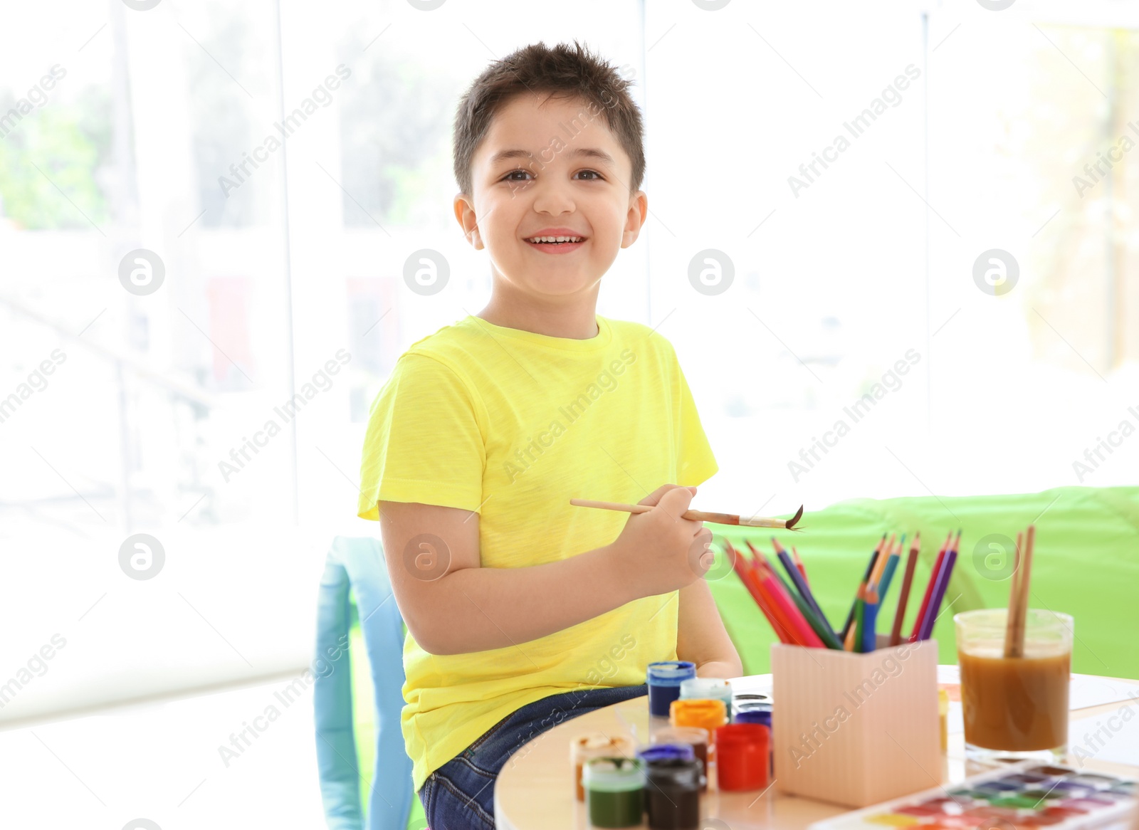 Photo of Cute little children painting at table in playing room