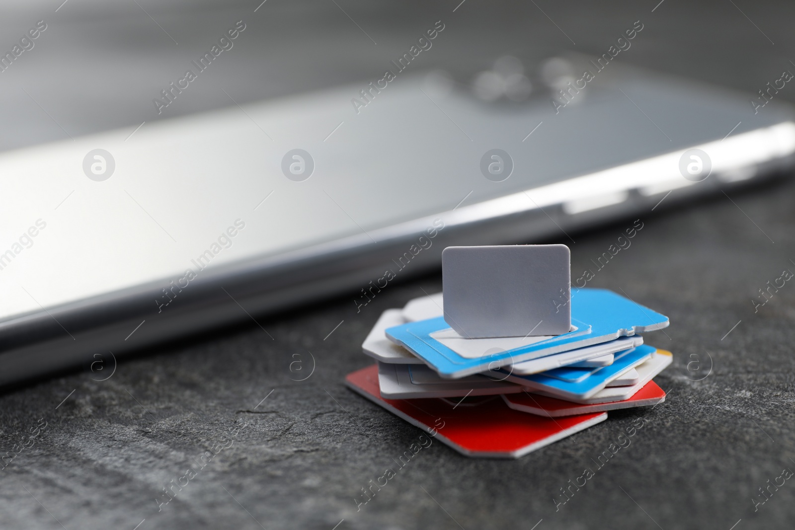 Photo of SIM cards and mobile phone on grey table, closeup