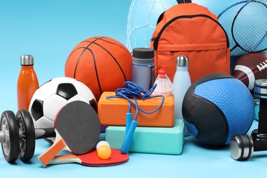 Many different sports equipment on light blue background, closeup