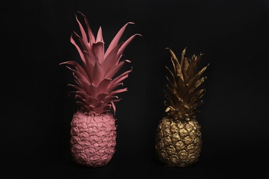 Gold and pink painted fresh pineapples on black background