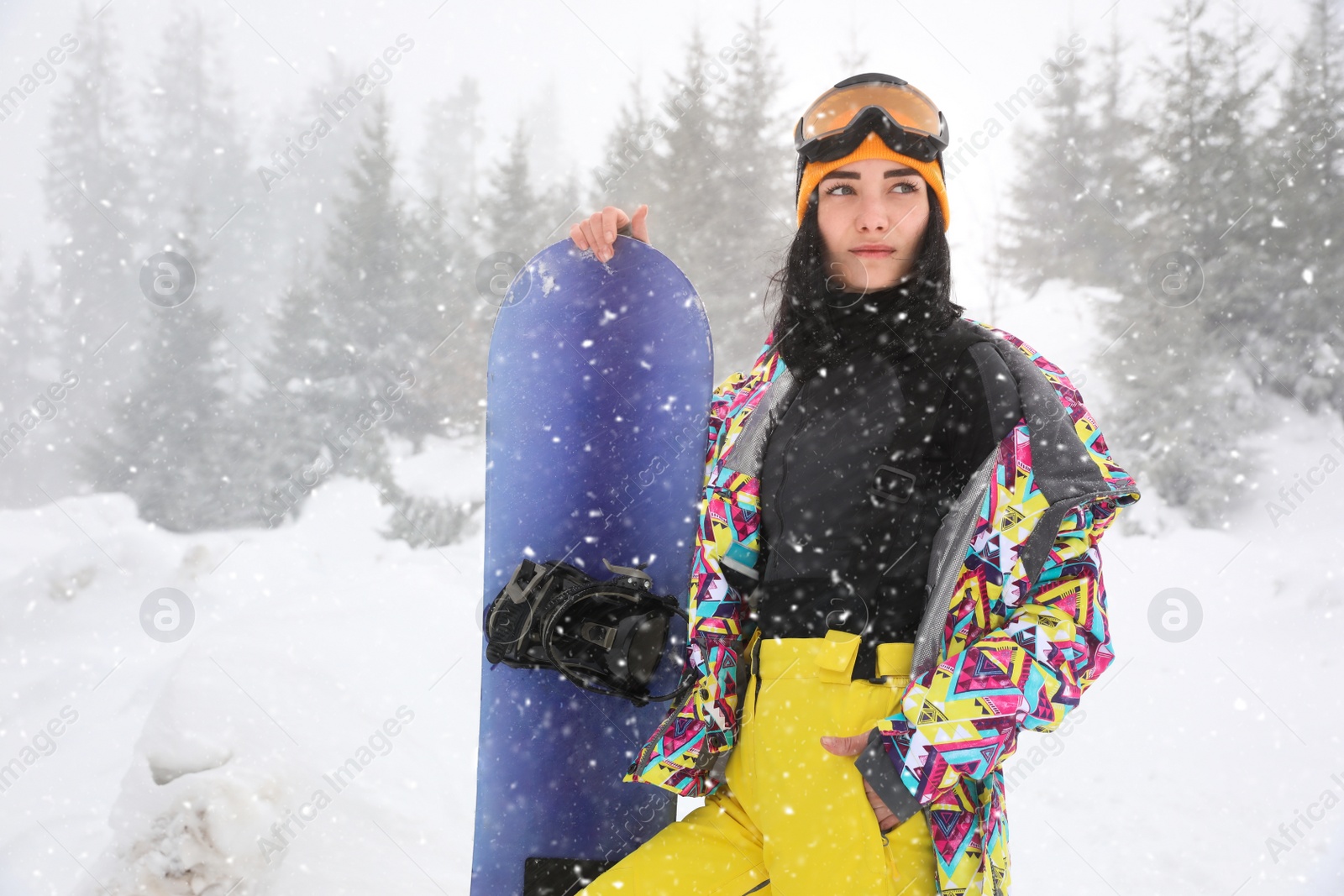 Photo of Young woman with snowboard wearing winter sport clothes outdoors