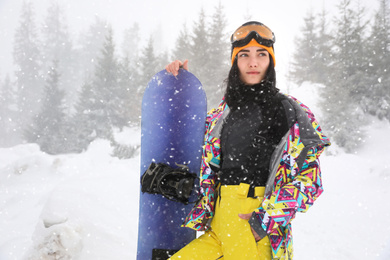 Young woman with snowboard wearing winter sport clothes outdoors