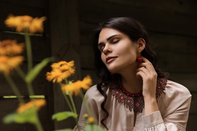 Beautiful woman wearing ornate beaded necklace in blooming garden. Ukrainian national jewelry