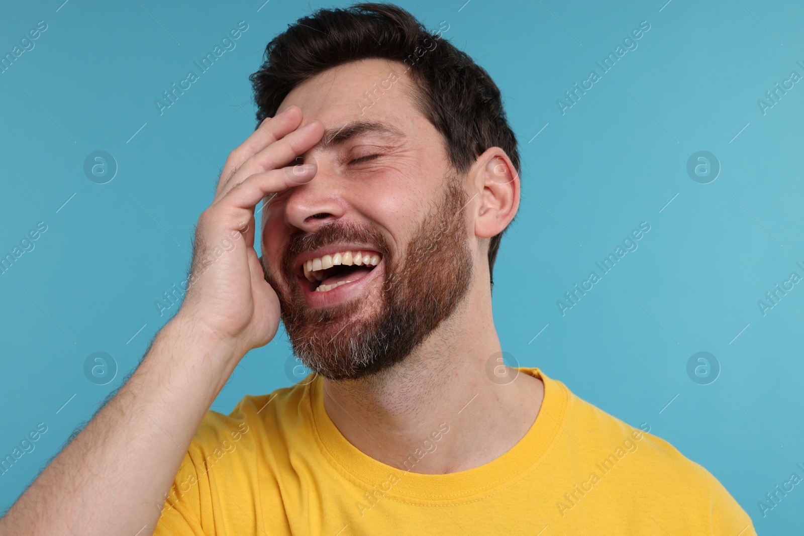 Photo of Handsome man laughing on light blue background, closeup