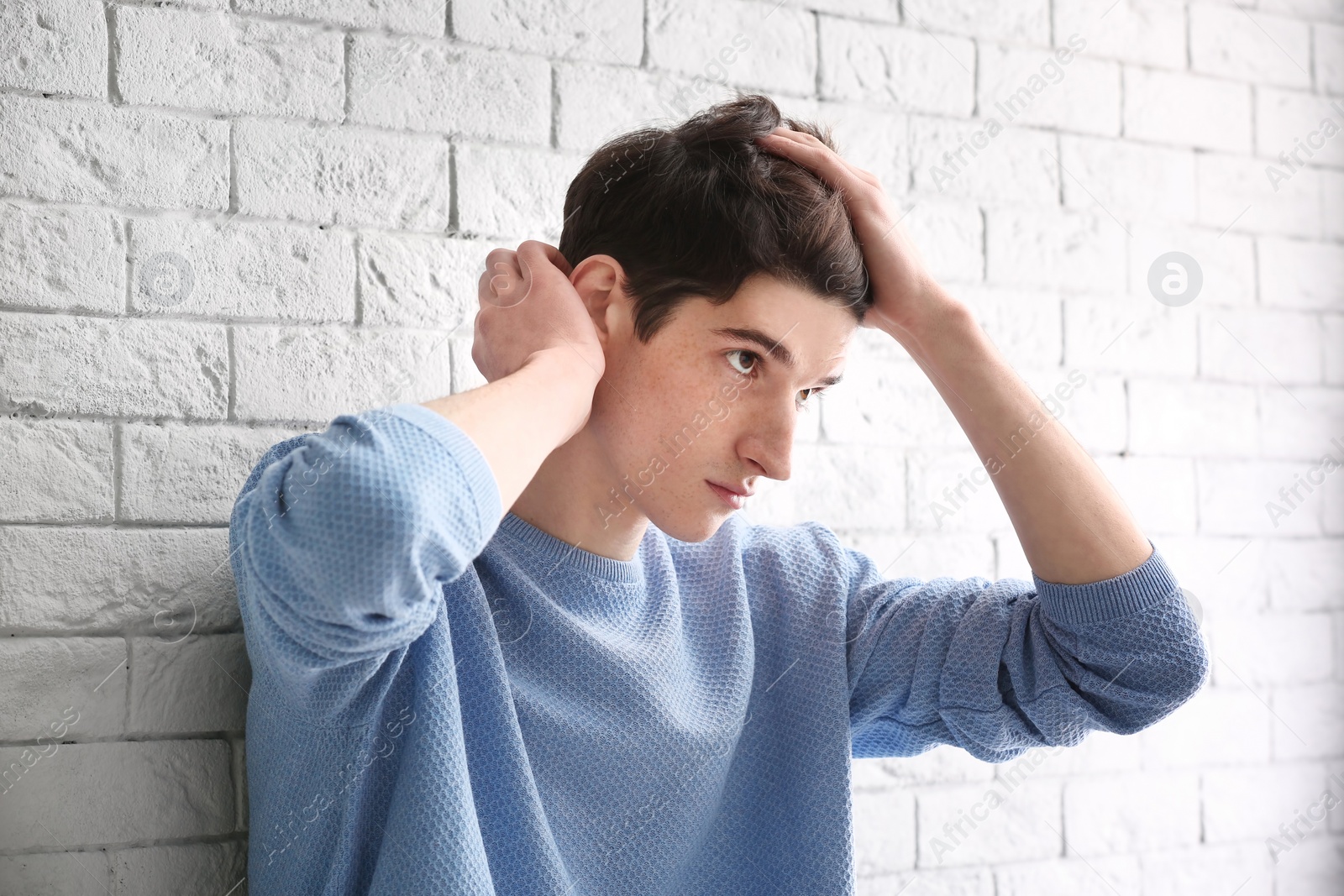 Photo of Portrait of young man with beautiful hair on brick wall background