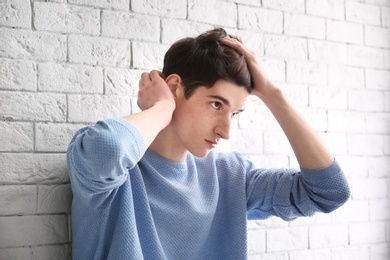 Photo of Portrait of young man with beautiful hair on brick wall background