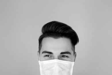 Image of Man wearing medical face mask on light background. Black and white photography