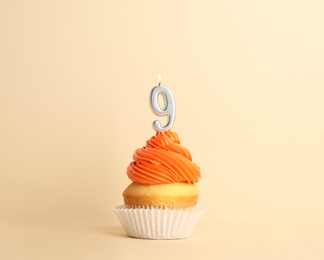 Photo of Birthday cupcake with number nine candle on beige background