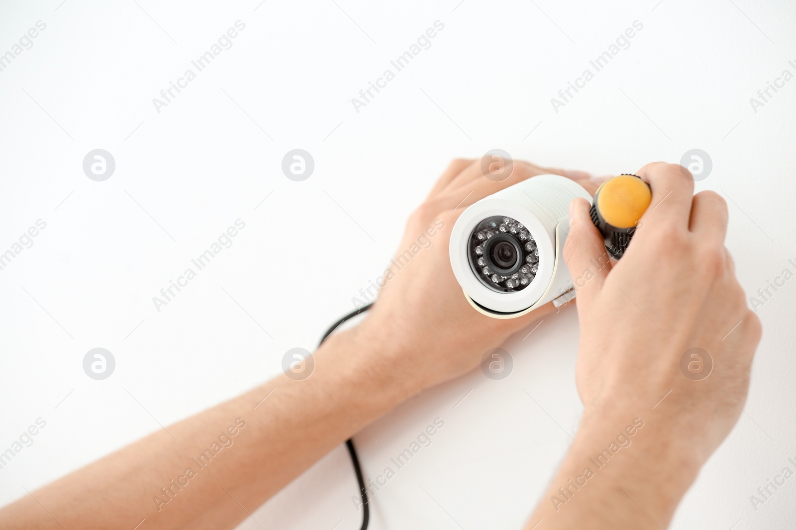 Photo of Technician installing CCTV camera on wall indoors, closeup