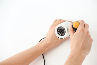 Photo of Technician installing CCTV camera on wall indoors, closeup