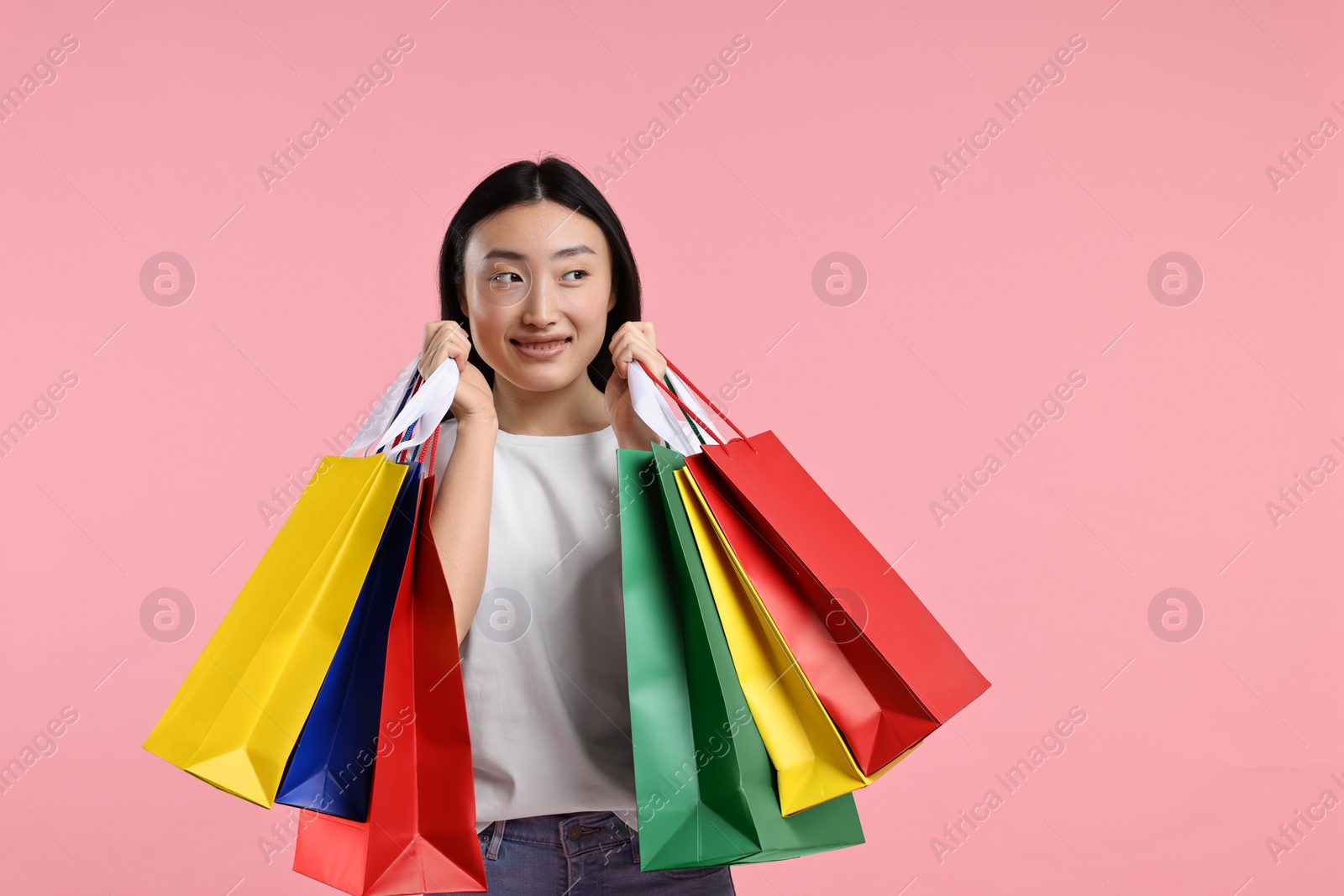 Photo of Happy woman with shopping bags on pink background. Space for text