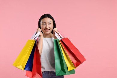 Happy woman with shopping bags on pink background. Space for text