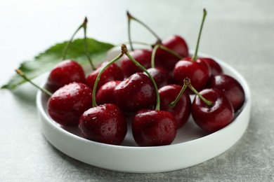 Fresh ripe cherries with water drops on light grey table, closeup