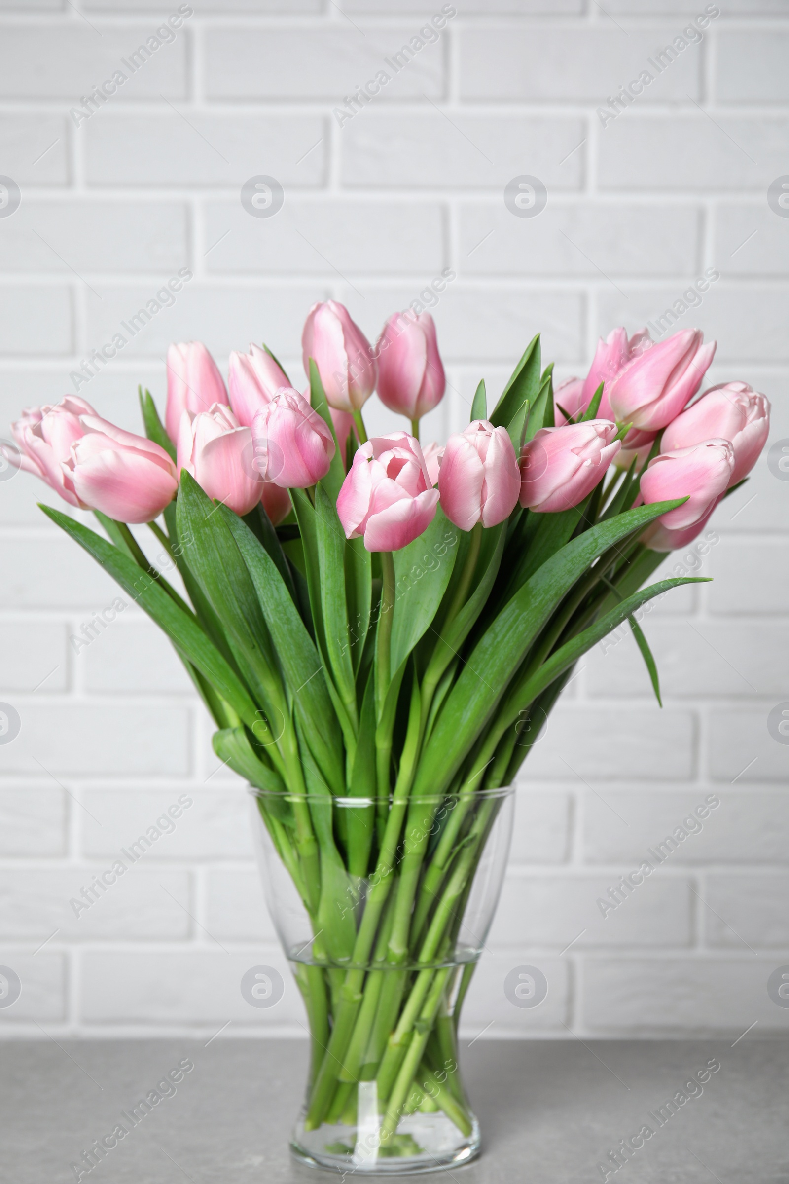 Photo of Beautiful pink spring tulips in vase on grey table