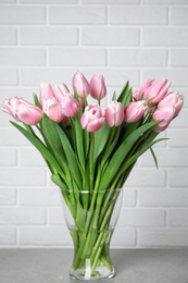 Beautiful pink spring tulips in vase on grey table