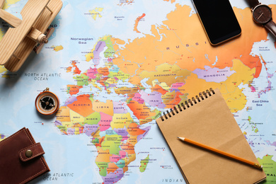 Photo of Flat lay composition with notebook and different items on world map. Trip planning