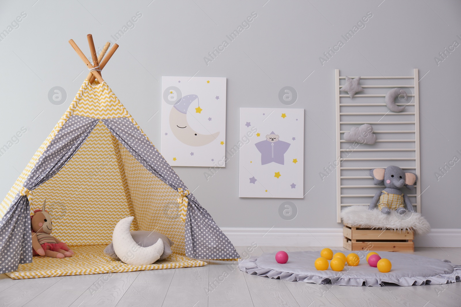 Photo of Stylish child's room interior with adorable paintings and play tent