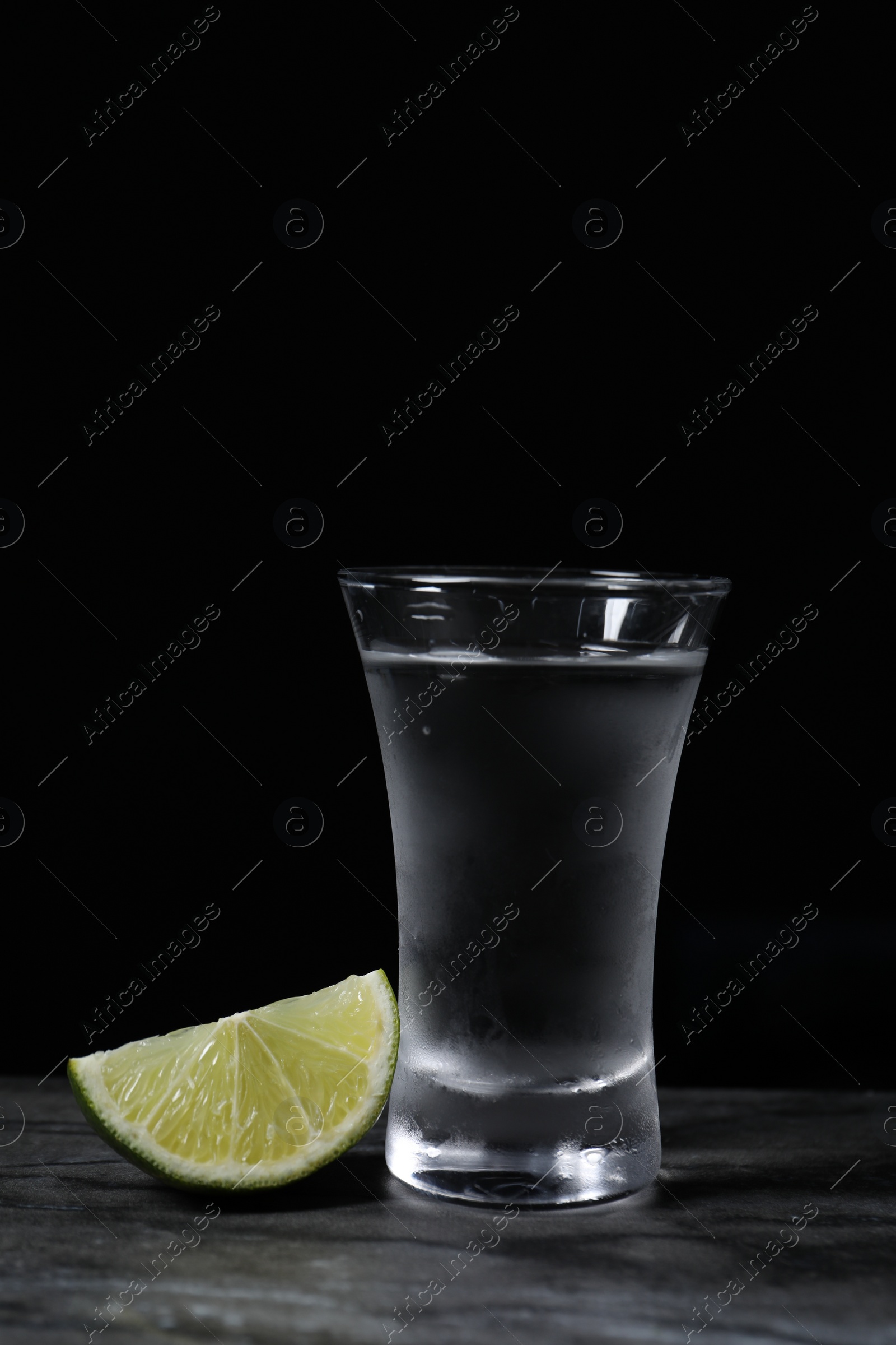 Photo of Shot of vodka with lime slice on grey table