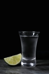 Photo of Shot of vodka with lime slice on grey table