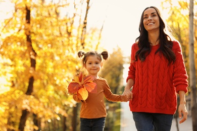 Happy woman with daughter walking in sunny autumn park