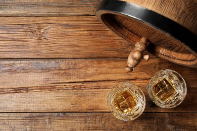 Photo of Glasses of whiskey and wooden barrel on table, flat lay. Space for text