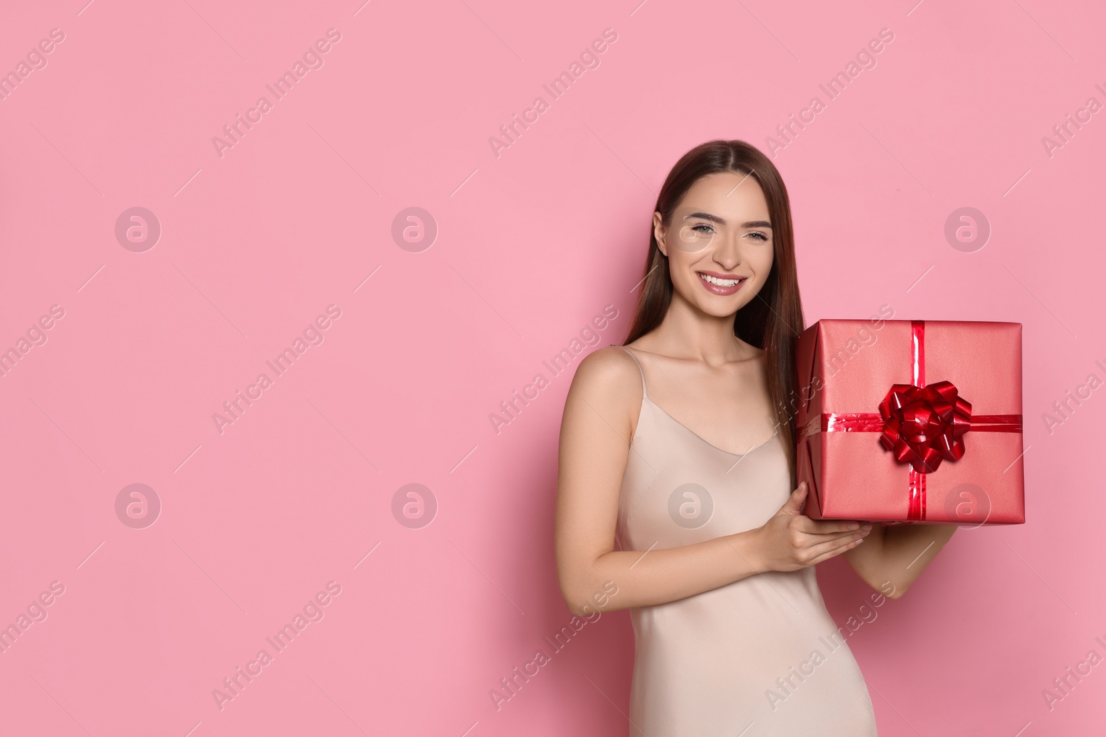 Photo of Portrait of happy young woman with gift box on pink background. Space for text