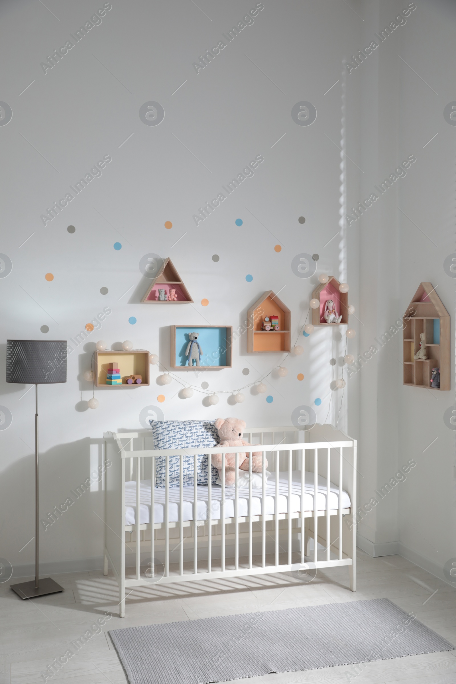 Photo of Cute children's room with house shaped shelves and crib. Interior design