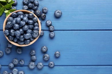Photo of Tasty fresh blueberries on blue wooden table, flat lay. Space for text