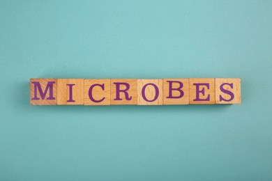 Word Microbes made with wooden cubes on light blue background, top view