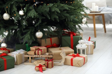 Beautifully wrapped gift boxes, wooden sleigh and lantern under Christmas tree indoors