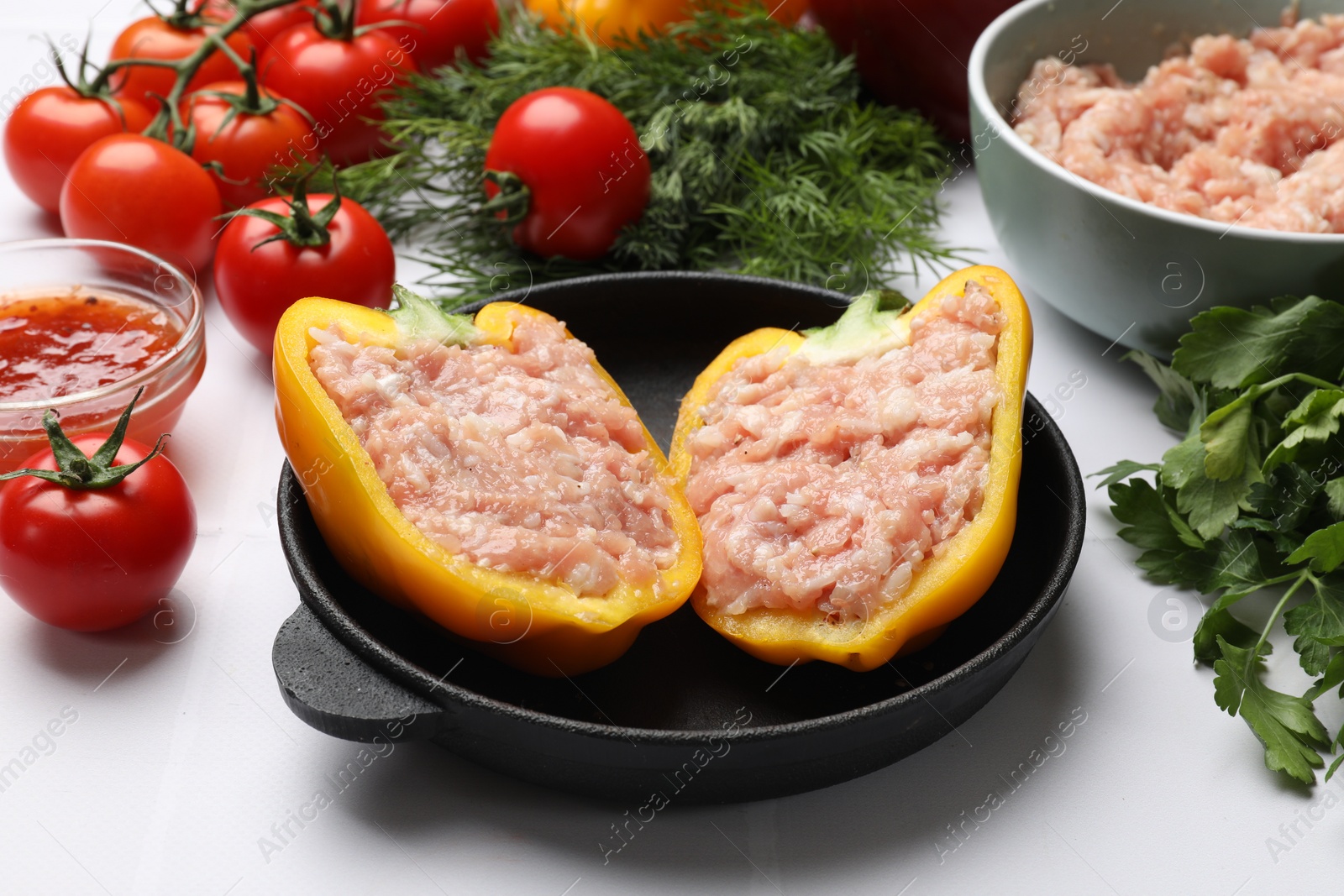 Photo of Raw stuffed peppers with ground meat and ingredients on white tiled table