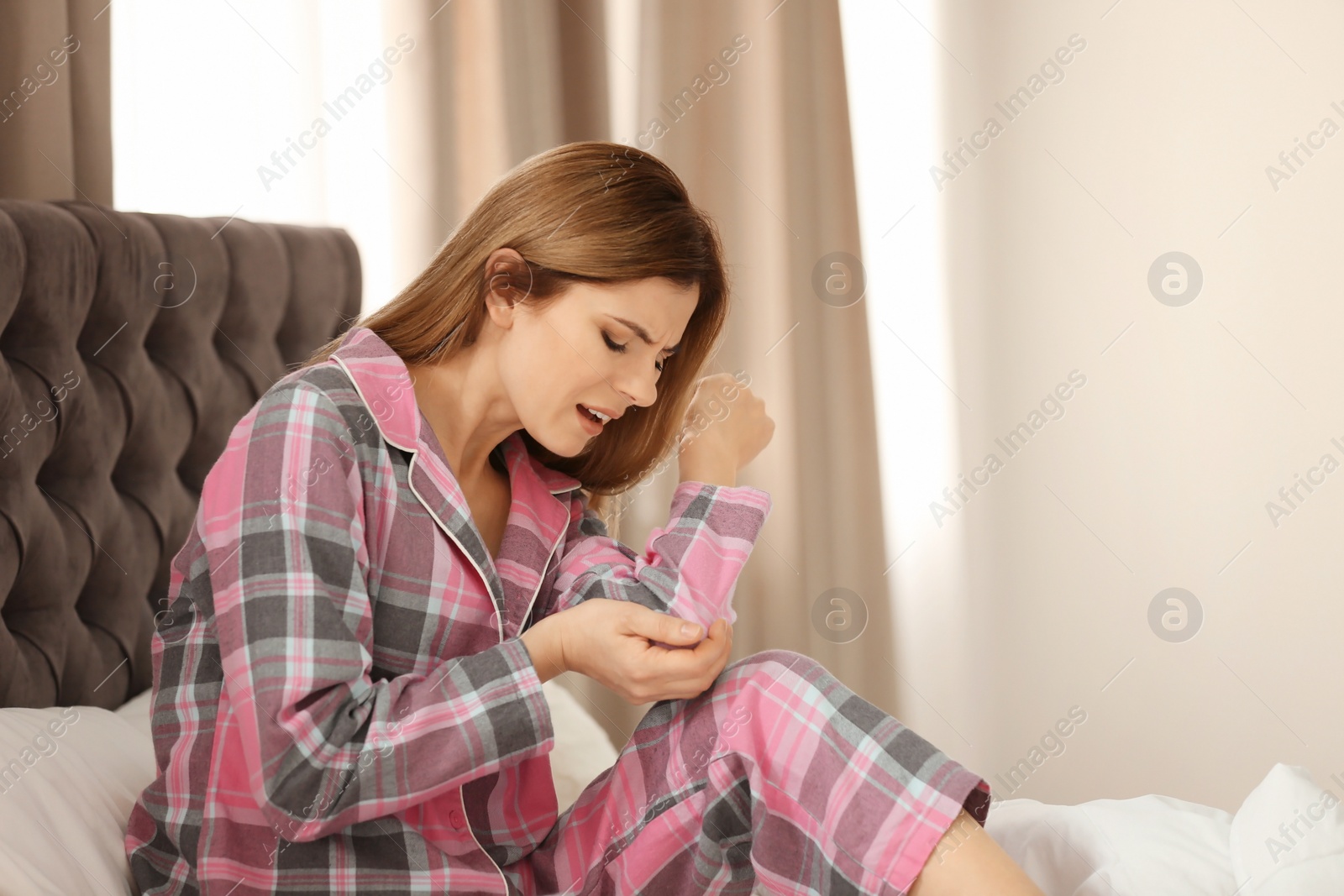 Photo of Woman suffering from elbow pain in bedroom