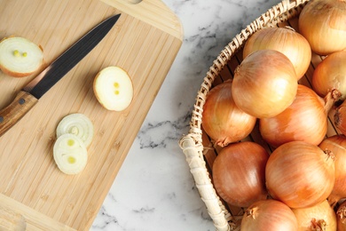 Photo of Flat lay composition with ripe onions in basket on marble table