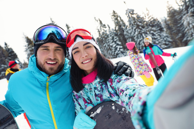 Photo of Happy couple taking selfie on snowy slope. Winter vacation