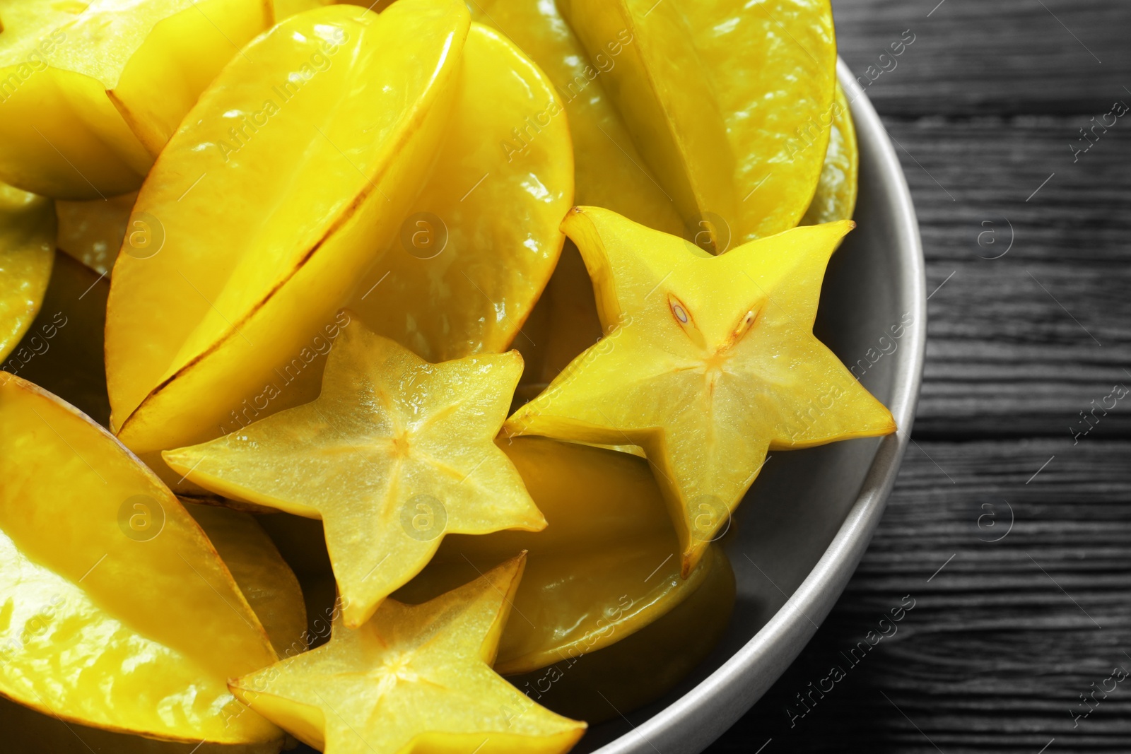 Photo of Delicious carambola fruits on black wooden table, closeup