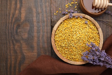 Fresh bee pollen granules, lavender, honey and dipper on wooden table, flat lay. Space for text