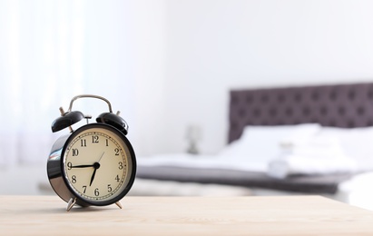 Photo of Alarm clock on table in bedroom. Time to wake up