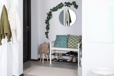 Photo of Hallway interior with stylish furniture and round mirror on light wall