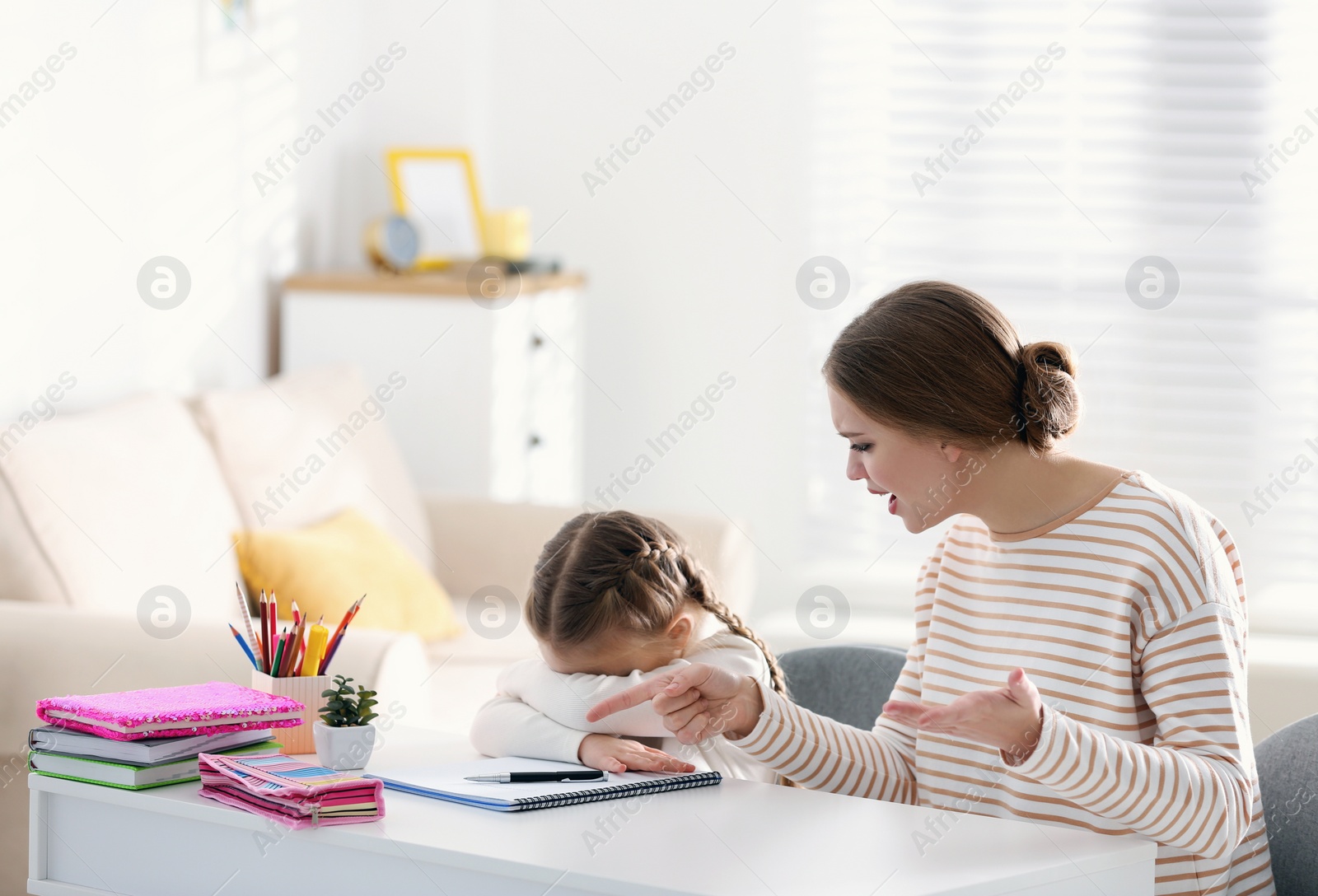 Photo of Mother scolding her daughter while helping with homework indoors