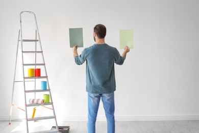 Photo of Young man choosing color for wall indoors