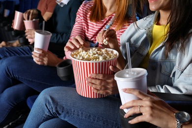 Young people eating popcorn during showtime in cinema theatre