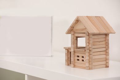 Photo of Wooden house on white shelf indoors, space for text. Educational toy for motor skills development