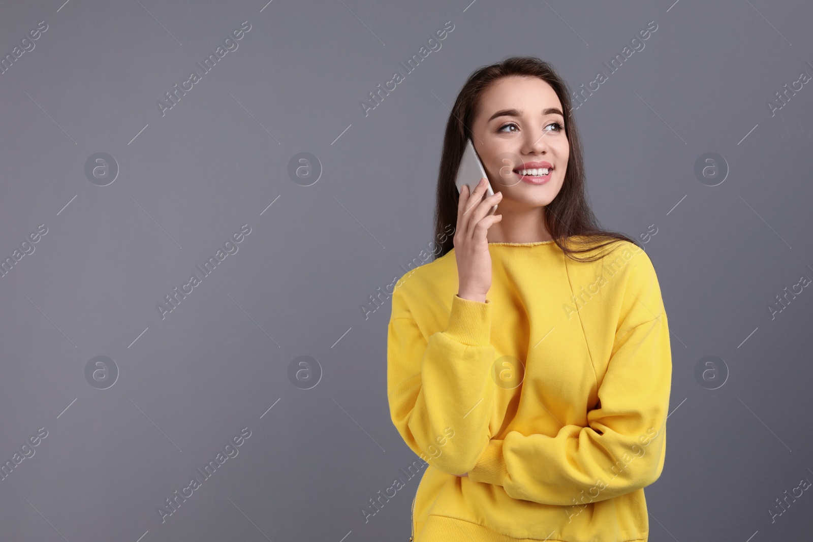 Photo of Young woman talking on phone against color background