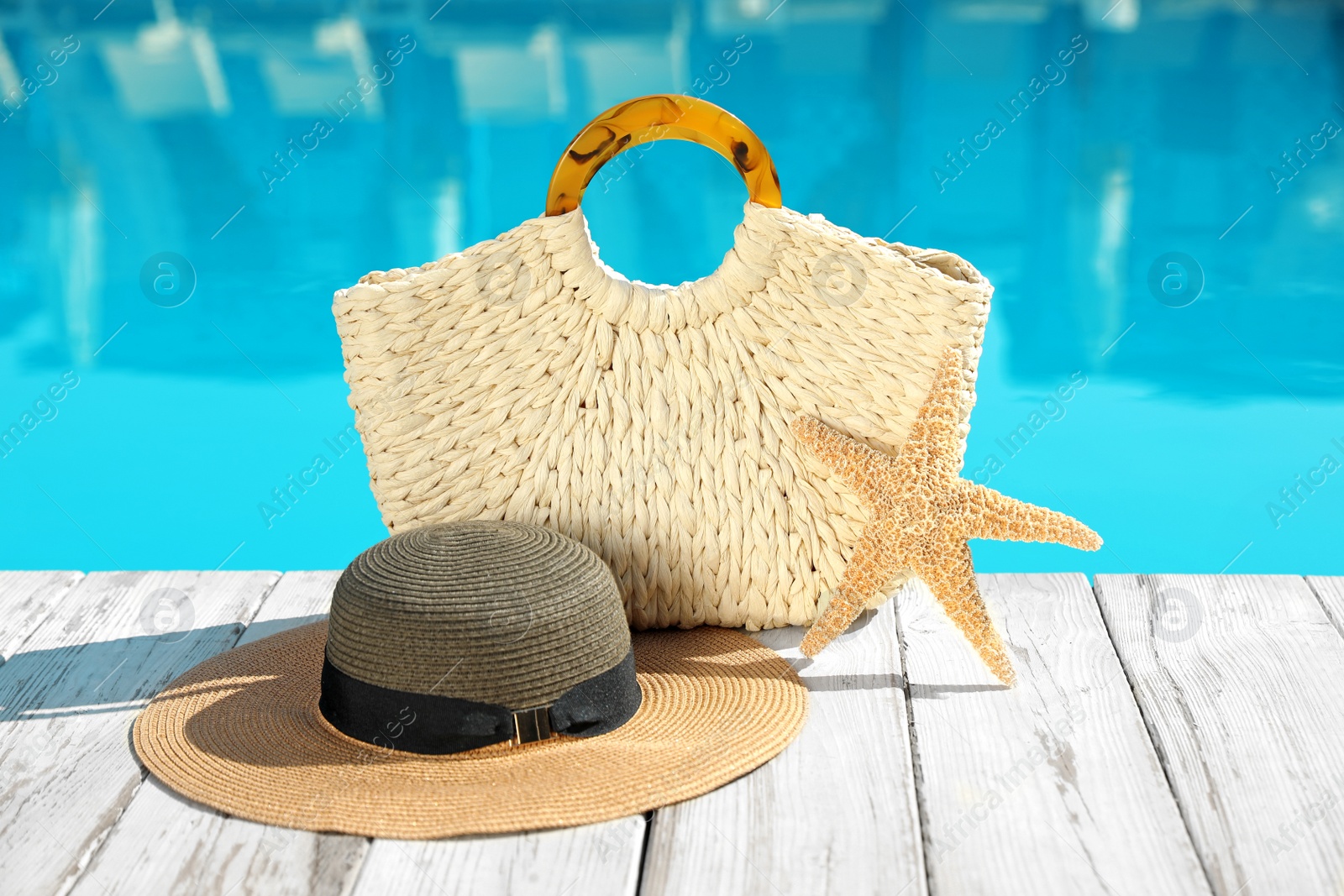 Photo of Beach accessories on wooden deck near outdoor swimming pool