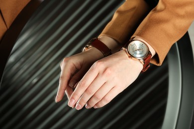 Photo of Woman wearing luxury wristwatch near mirror, closeup