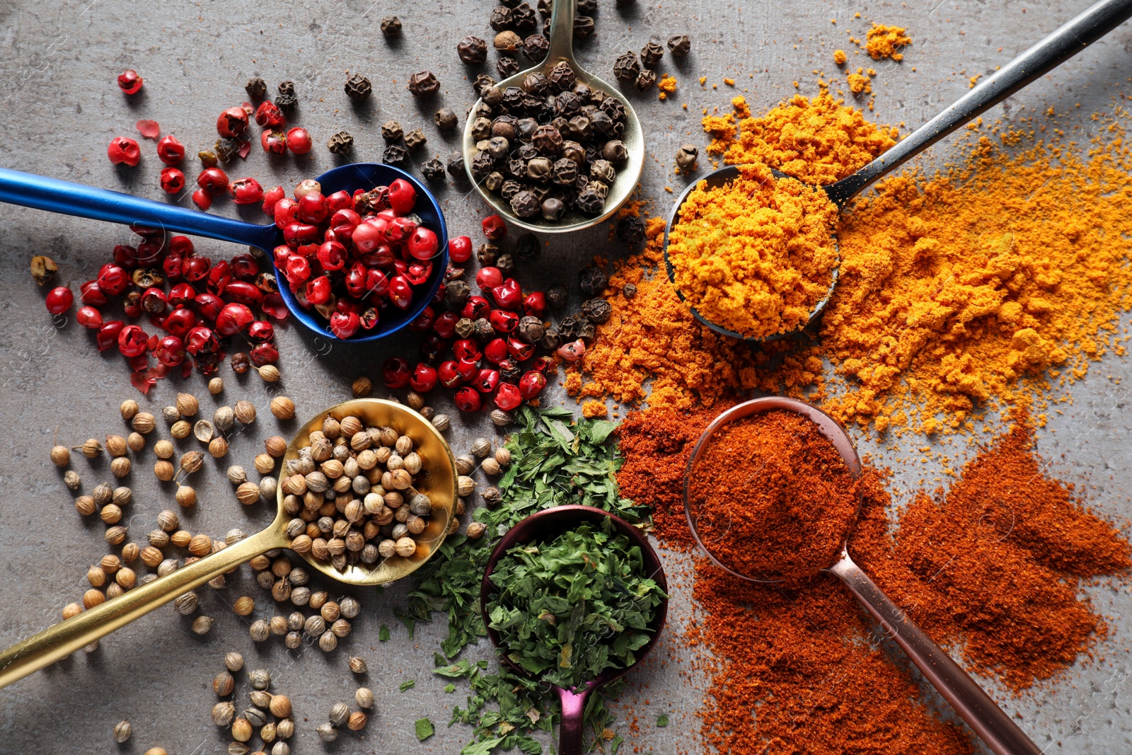 Photo of Flat lay composition of different spices and spoons on grey textured table