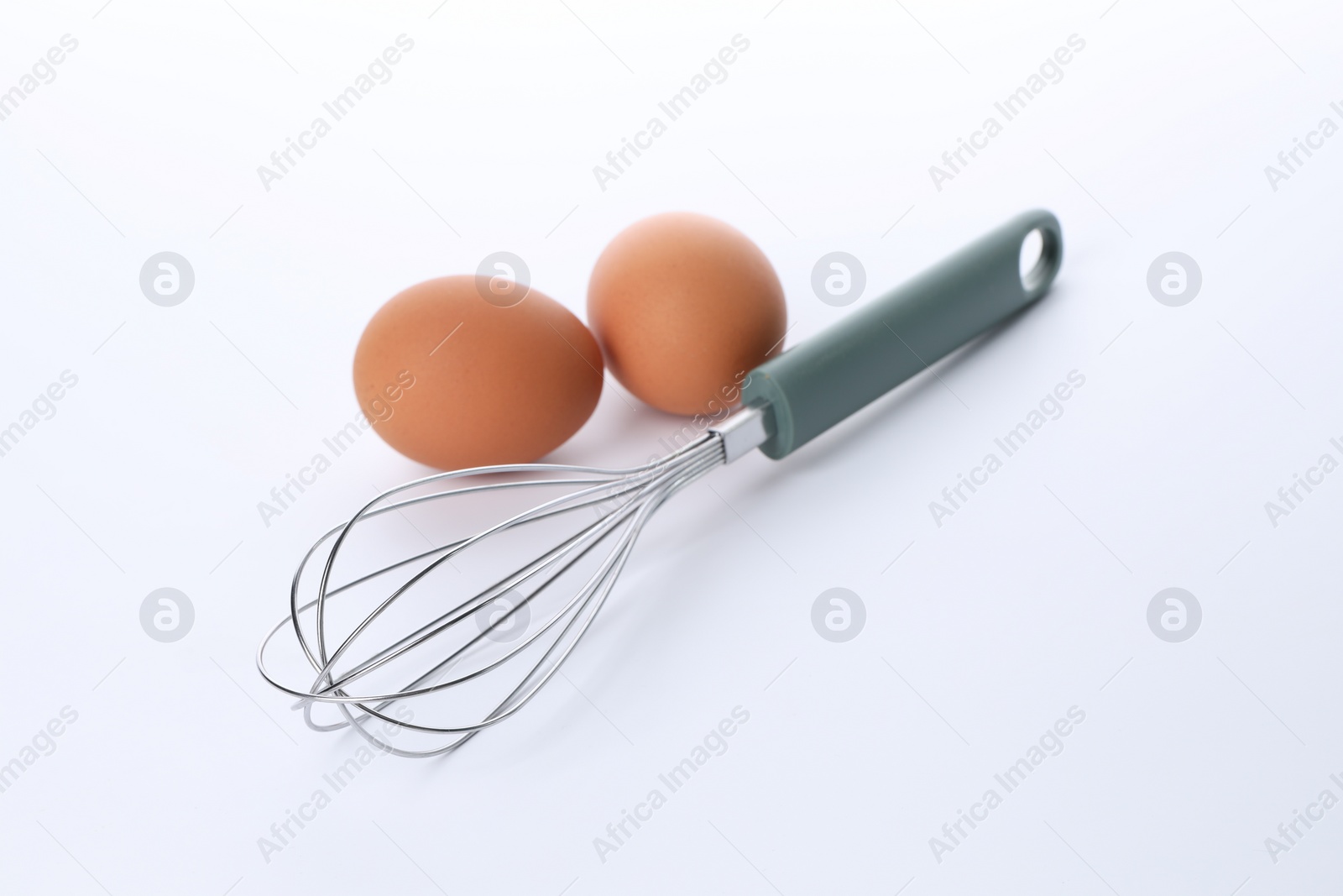 Photo of Whisk and raw eggs isolated on white